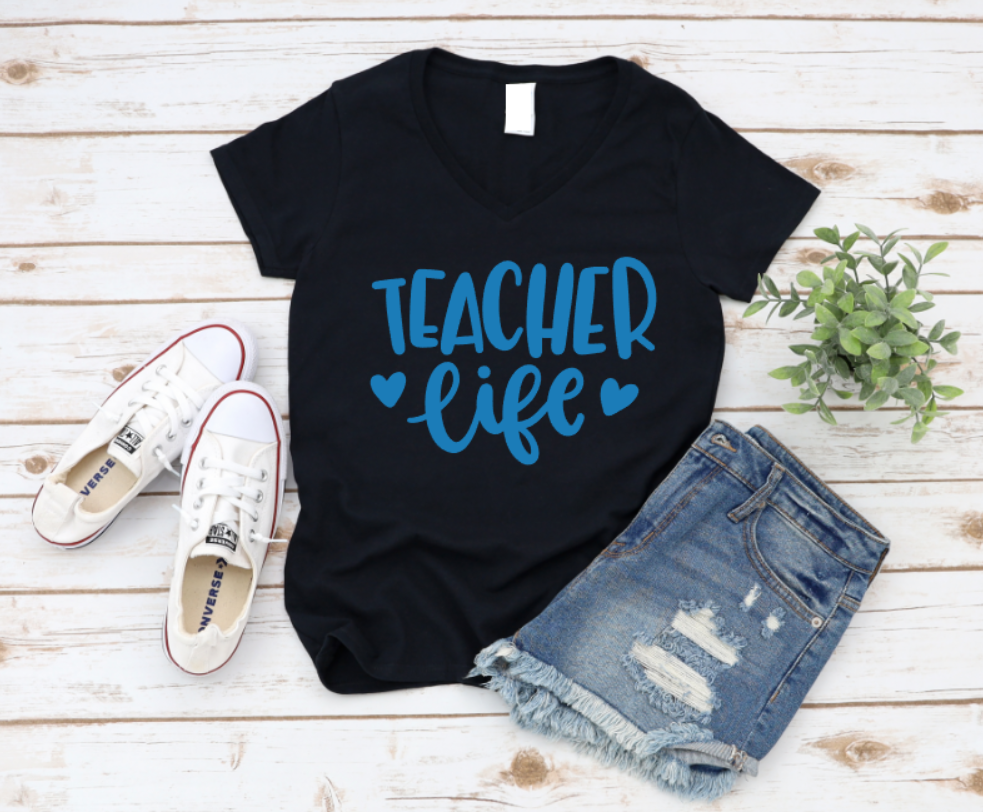 Black t-shirt with 'Teacher Life' text, white sneakers, and denim shorts on a wooden surface. www.missmafia.com