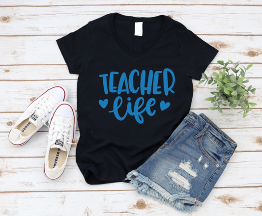 Black t-shirt with 'Teacher Life' text, white sneakers, and denim shorts on a wooden surface. www.missmafia.com
