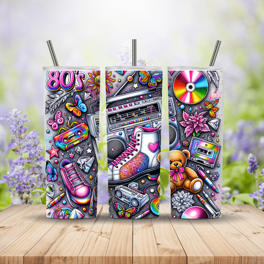 Three tumblers with 80s-themed designs on a wooden surface with a blurred floral background.