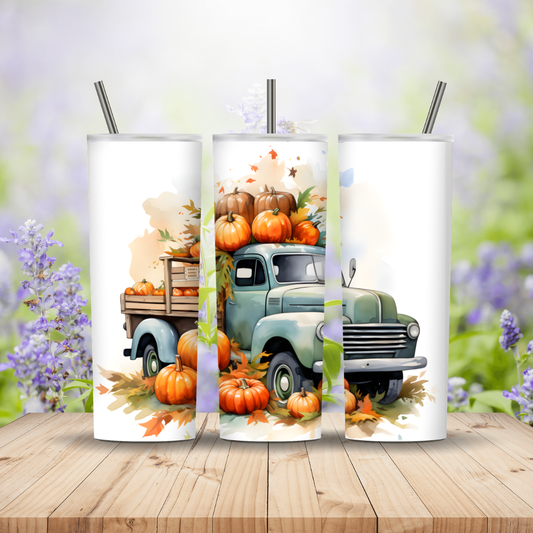 Three tumblers with a vintage truck and pumpkin design on a wooden surface with a floral background.
