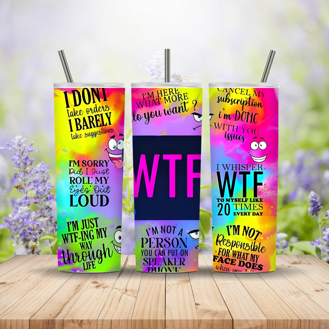 Three colorful tumblers with humorous text designs on a wooden surface with a blurred floral background.
