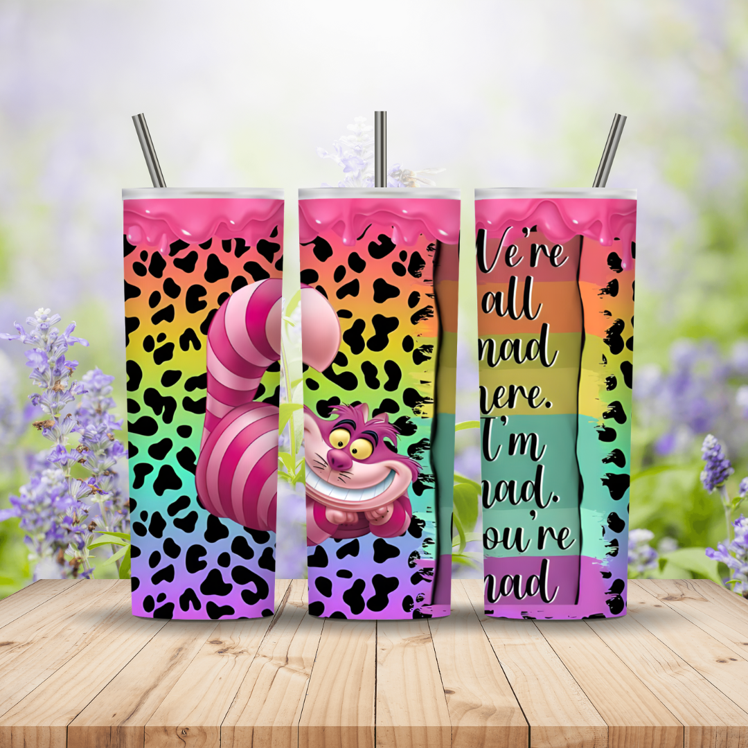 Three colorful tumblers with a character design and text on a wooden surface with a blurred floral background.