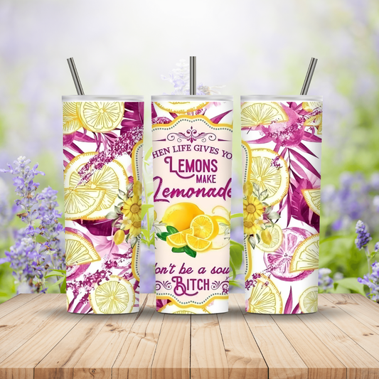 Three colorful tumblers with lemon designs and text on a wooden surface with a blurred floral background.