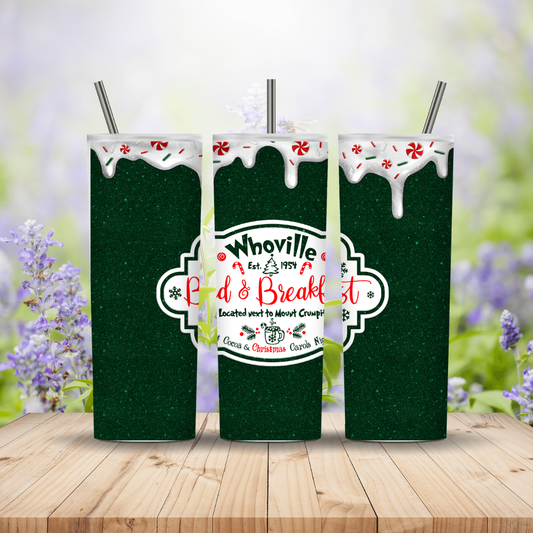 Three green tumblers with 'Whoville Bed & Breakfast' logo on a wooden surface with a floral background.