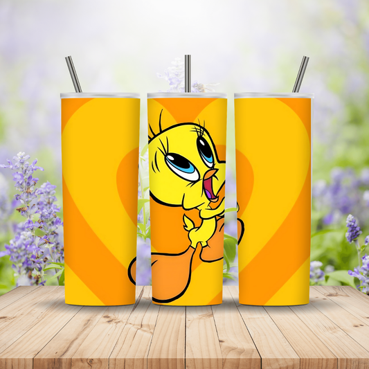 Three tumblers with a cartoon character on an orange background, placed on a wooden surface with a blurred floral background.