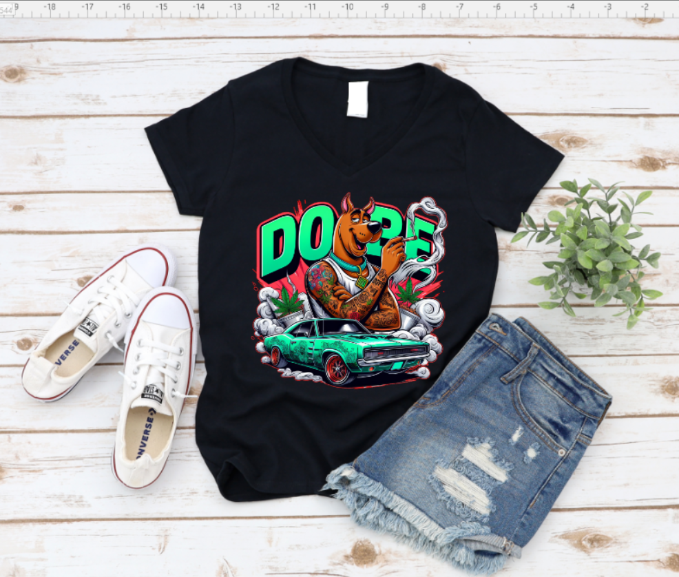 Black t-shirt with a graphic design of a dog and car, paired with white sneakers and denim shorts on a wooden surface.