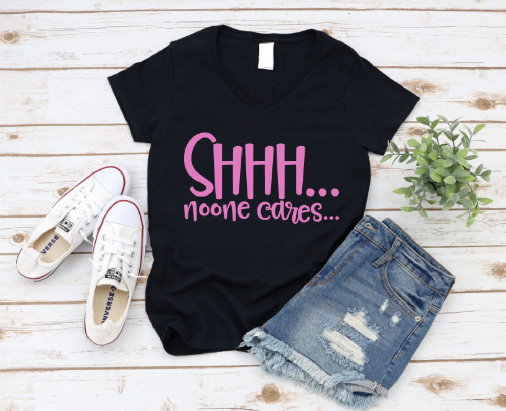 Black t-shirt with pink text 'SHHH... noone cares...' on a wooden surface with sneakers and shorts. www.missmafia.com