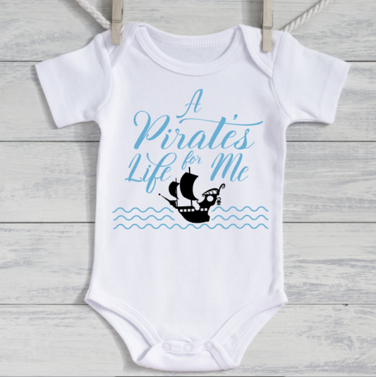 White baby onesie with blue text and ship graphic on a wooden surface
