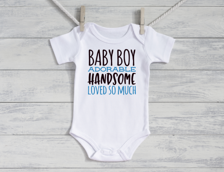 White baby onesie with text on a wooden surface