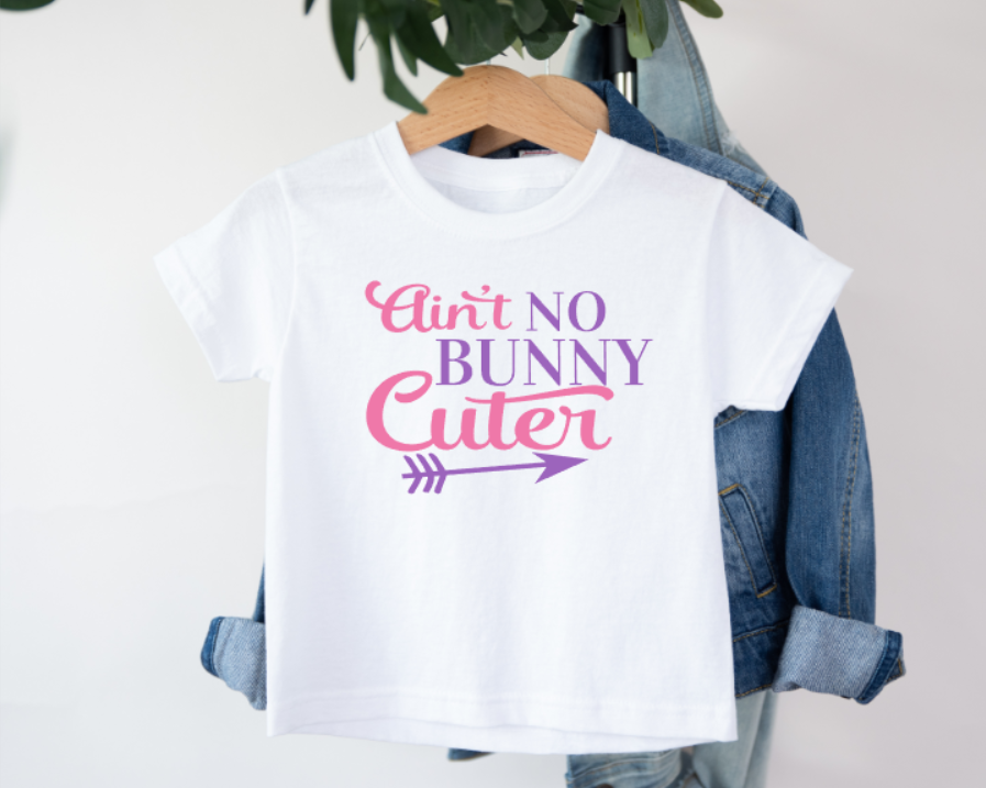White kids t-shirt with black text that reads “Ain’t No Bunny Cuter,” featuring a fun bunny design, perfect for Easter or cute everyday wear
