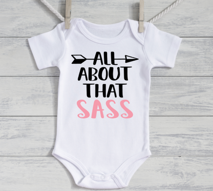 White baby onesie with 'All About That Sass' text on a wooden background
