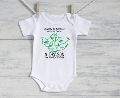 White baby onesie with a dragon graphic and text on a wooden surface