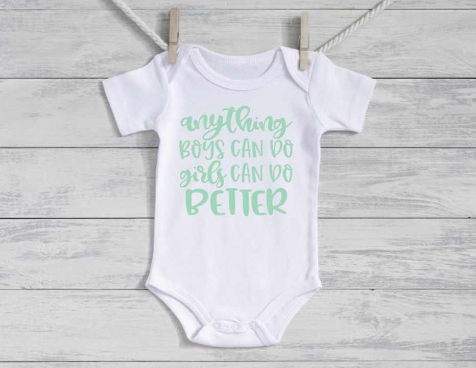 White baby onesie with green text on a wooden surface