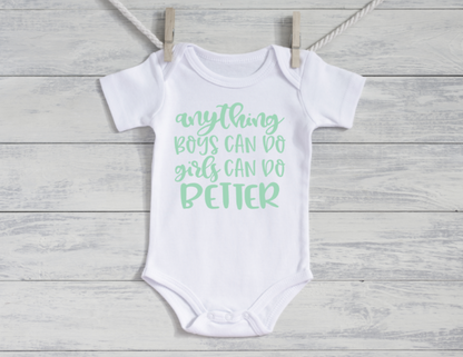 White baby onesie with green text on a wooden surface