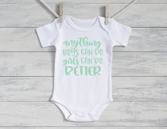 White baby onesie with green text on a wooden surface