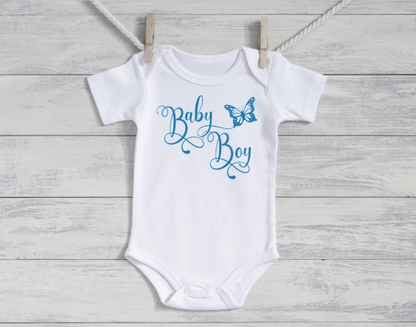 White baby onesie with 'Baby Boy' text and butterfly graphic on a wooden surface