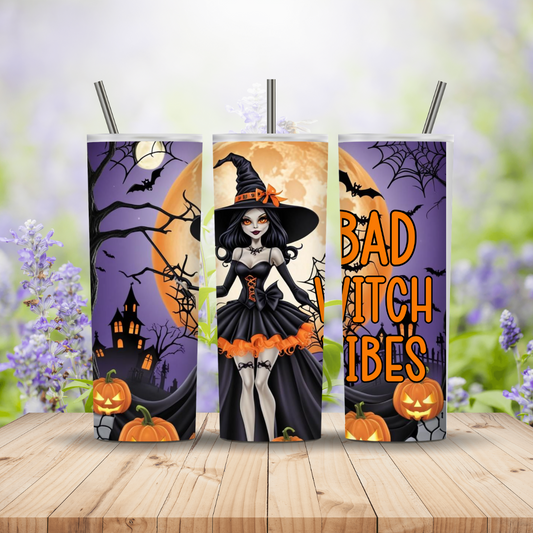 Three Halloween-themed tumblers with witch designs on a wooden surface.