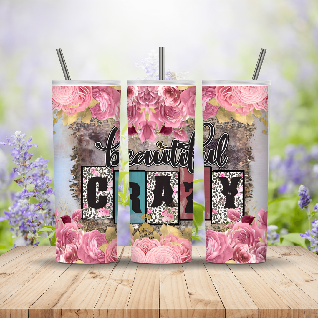 Three tumblers with floral designs and text on a wooden surface with a blurred natural background