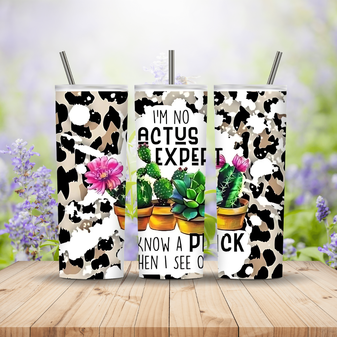 Three tumblers with cow print design and text on a wooden surface with blurred floral background