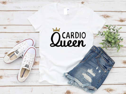 White t-shirt with “Cardio Queen” text and a gold crown, styled with denim shorts and white sneakers on a wooden background.