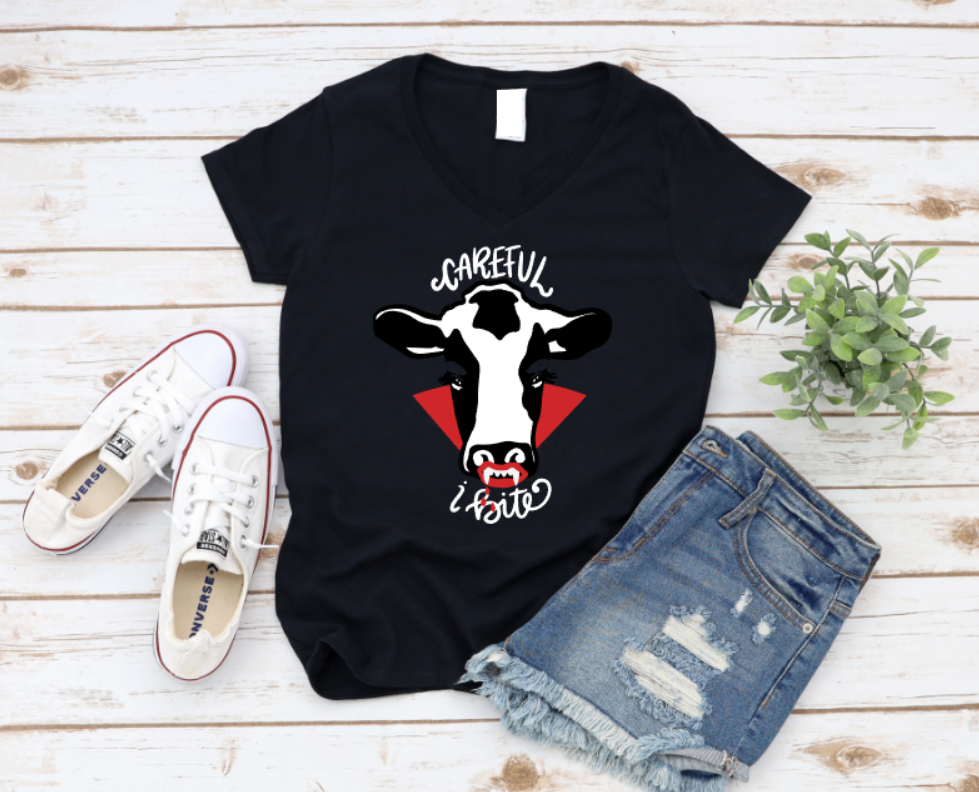 Black t-shirt with a cow graphic and text, paired with white sneakers and denim shorts on a wooden surface. www.missmafia.com