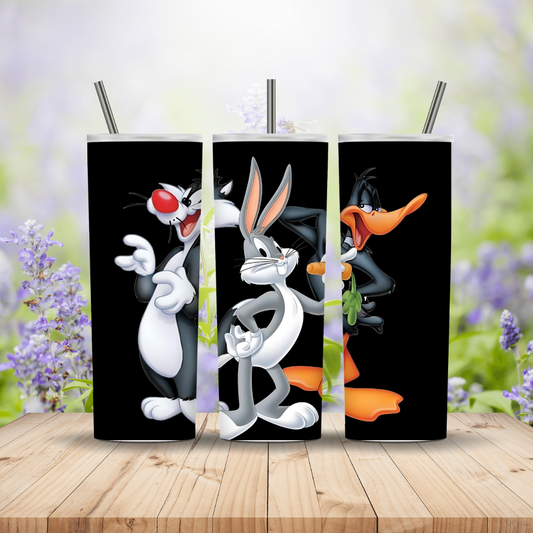 Three cartoon character tumblers with straws on a wooden surface with a blurred floral background.
