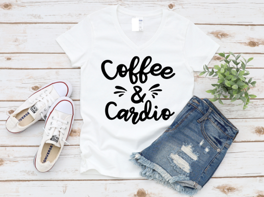 White t-shirt with “Coffee & Cardio” text in white, styled with ripped denim shorts and white sneakers on a wooden surface.