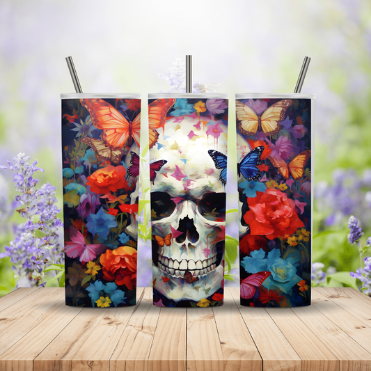 Three colorful tumblers with skull and butterfly designs on a wooden surface with a floral background.