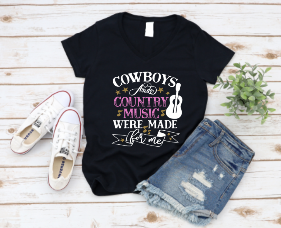 Black t-shirt with "Cowboys and Country Music Were Made for Me" graphic, featuring stars, a guitar, and musical notes, styled with denim shorts and white Converse on a wooden background.