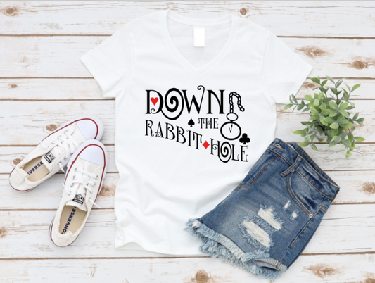 White tank top with text, white sneakers, and denim shorts on a wooden surface.