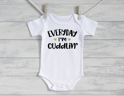 White baby onesie with text on a wooden background