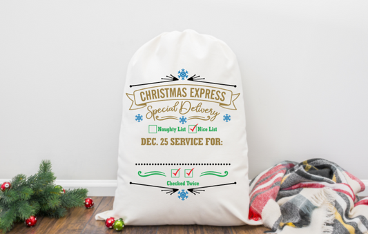 White Santa sack with Christmas-themed text on a wooden floor with decorative items.
