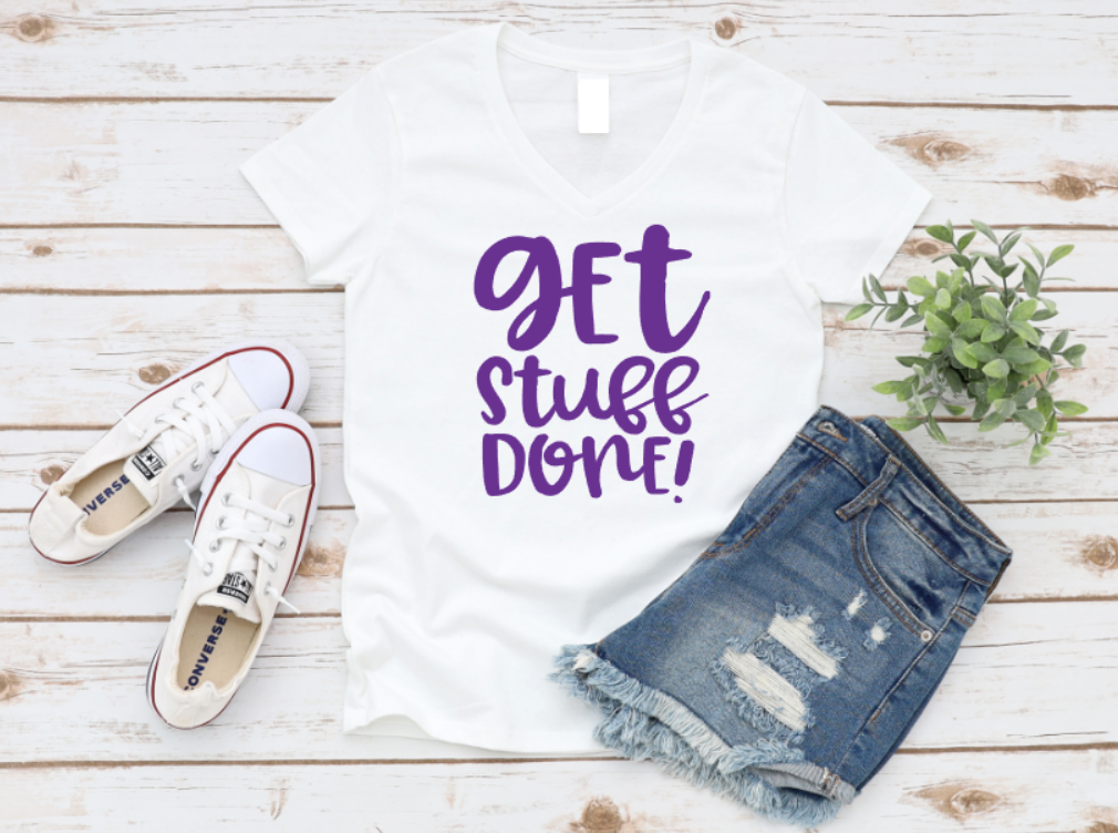 White t-shirt with 'GET STUFF DONE!' text, white sneakers, and denim shorts on a wooden surface.
