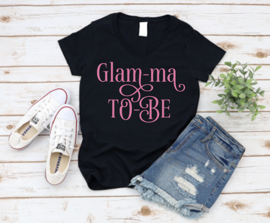 Black t-shirt with the phrase “Glam-Ma To Be” in bold script, ideal for pregnancy announcements or baby showers for stylish grandmothers-to-be