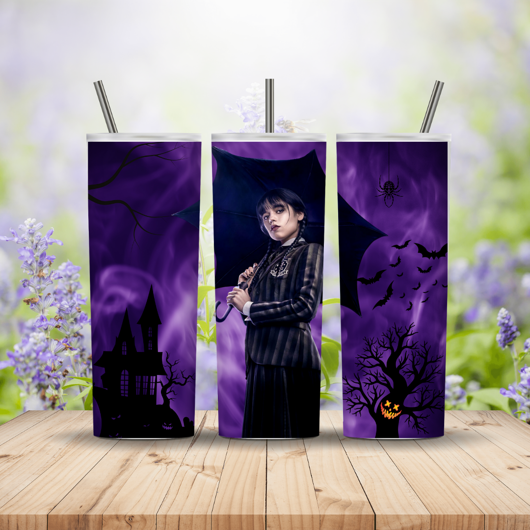 Three purple tumblers with Halloween-themed designs on a wooden surface with a blurred floral background.