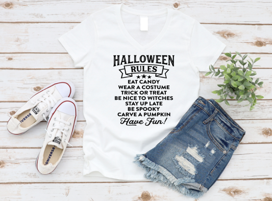White t-shirt with Halloween rules text, denim shorts, and white sneakers on a wooden surface.
