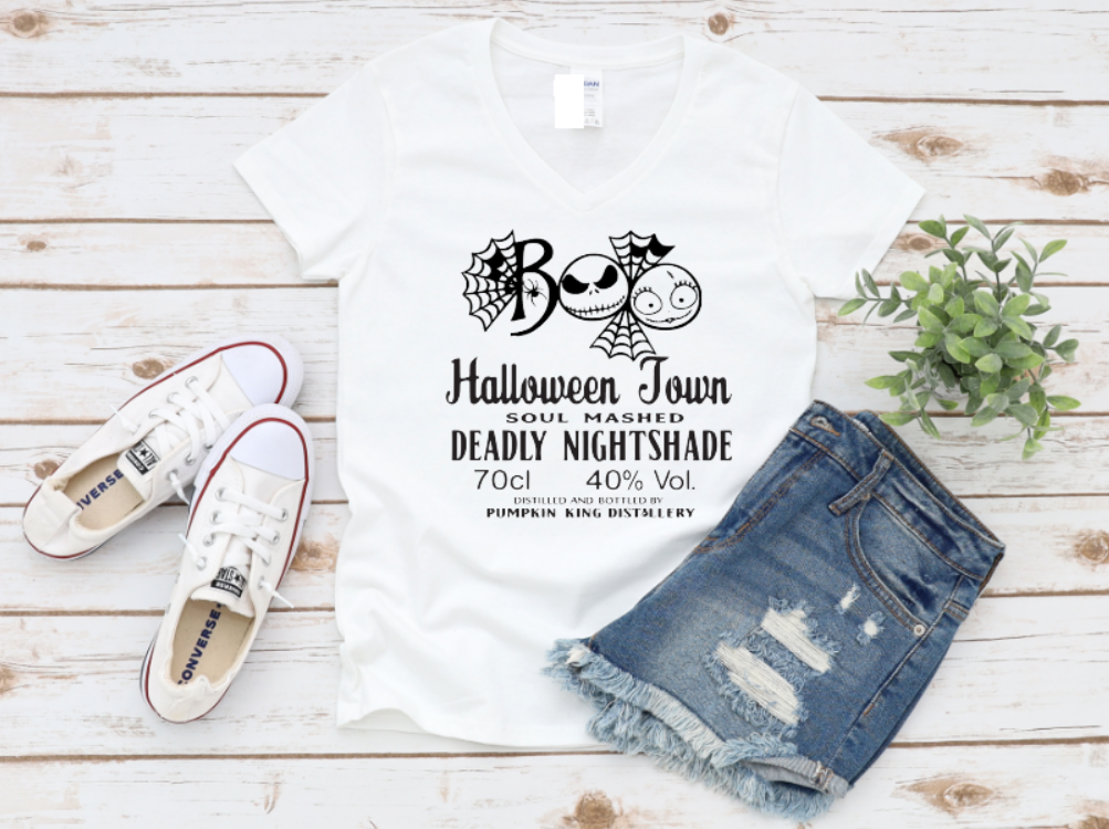 White t-shirt with "Boo" Halloween Town and Nightshade potion label design, styled with denim shorts and white sneakers on a wooden background.