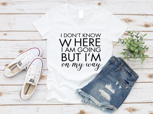 White t-shirt with text, white sneakers, and denim shorts on a wooden surface.