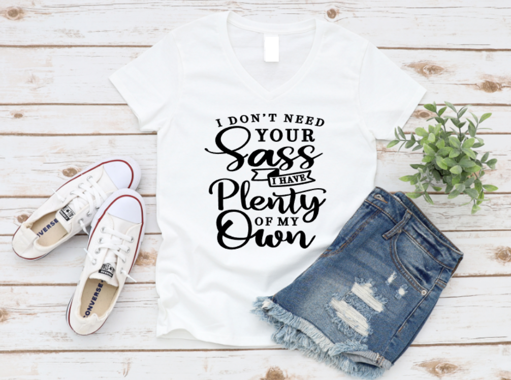 White tank top with text, white sneakers, and denim shorts on a wooden surface.