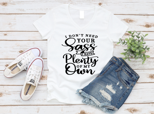White tank top with text, white sneakers, and denim shorts on a wooden surface.