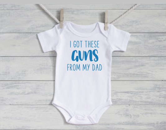 White baby onesie with blue text on a wooden surface