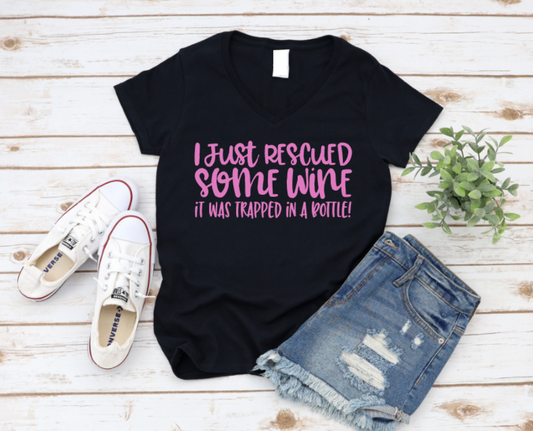 Black t-shirt with pink text, white sneakers, and denim shorts on a wooden surface.