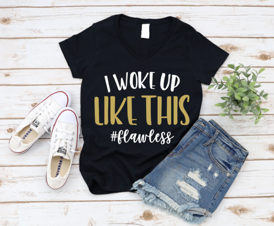 Black t-shirt with 'I woke up like this #flawless' text, paired with white sneakers and denim shorts on a wooden surface. Shop at www.missmafia.com
