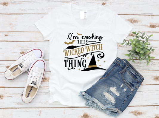 White t-shirt with 'I'm crushing this wicked witch thing' text, white sneakers, and denim shorts on a wooden surface. shop now www.missmafia.com