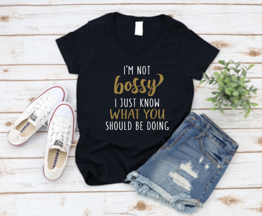 Black t-shirt with gold text, white sneakers, and denim shorts on a wooden surface. www.missmafia.com