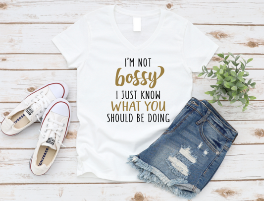 White t-shirt with 'I'm not bossy I just know what you should be doing' text, white sneakers, and denim shorts on a wooden surface. www.missmafia.com
