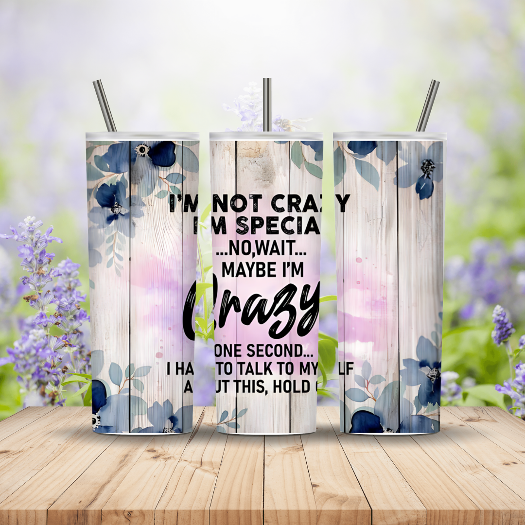 Three tumblers with floral designs and text on a wooden surface with blurred flowers in the background.