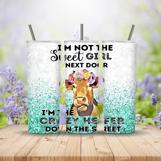 Three tumblers with a cow design and text on a wooden surface with a floral background