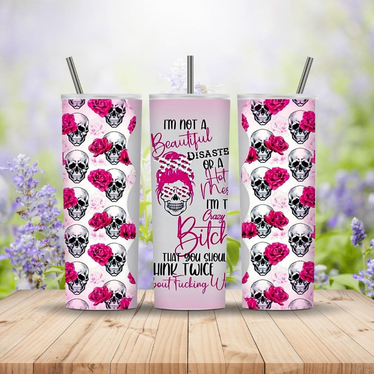 Three tumblers with skull and rose design on a wooden surface with a blurred floral background