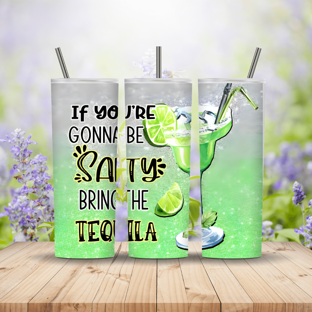 Three green tumblers with a tequila-themed design and text on a wooden surface with a blurred floral background.